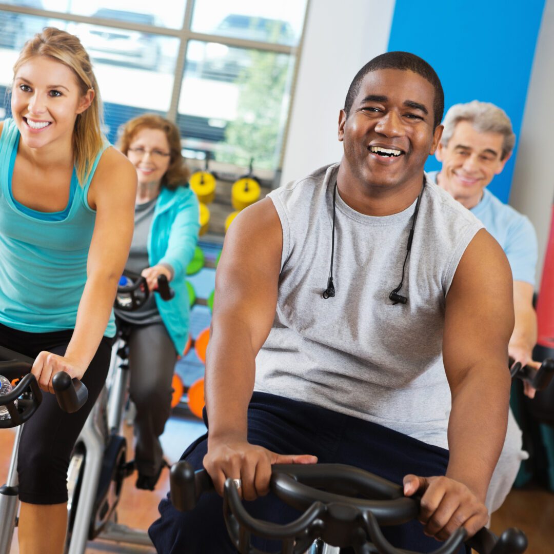A group of people riding on stationary bikes in a gym.